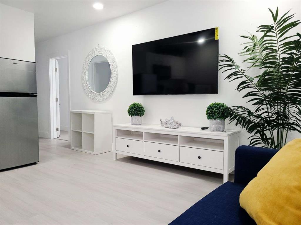 A living room features a wall-mounted television, white media console, and a blue sofa — 2519 W WALNUT, TAMPA, FL