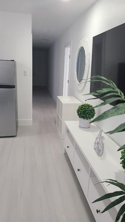 A hallway leads past a refrigerator, a white media console, and a circular wall mirror — 2519 W WALNUT, TAMPA, FL