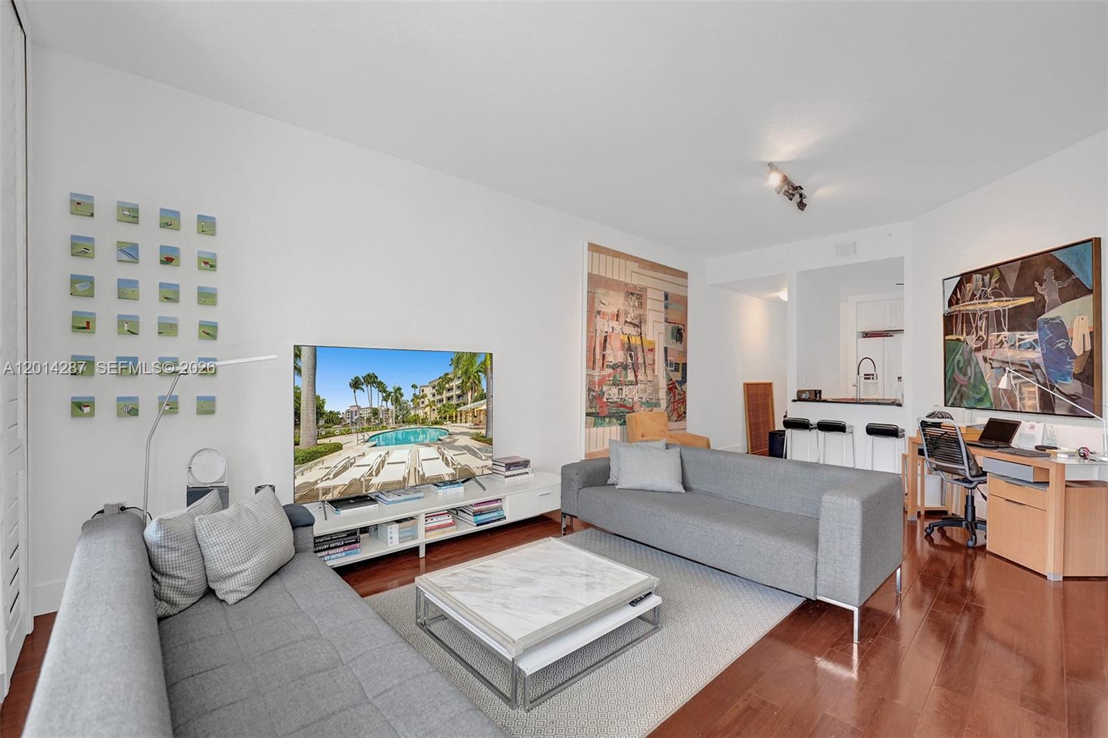 A living room features two gray sofas, a marble coffee table, and a home office area — 715 Crandon Blvd # 406, Key Biscayne FL 33149, KEY BISCAYNE, FL