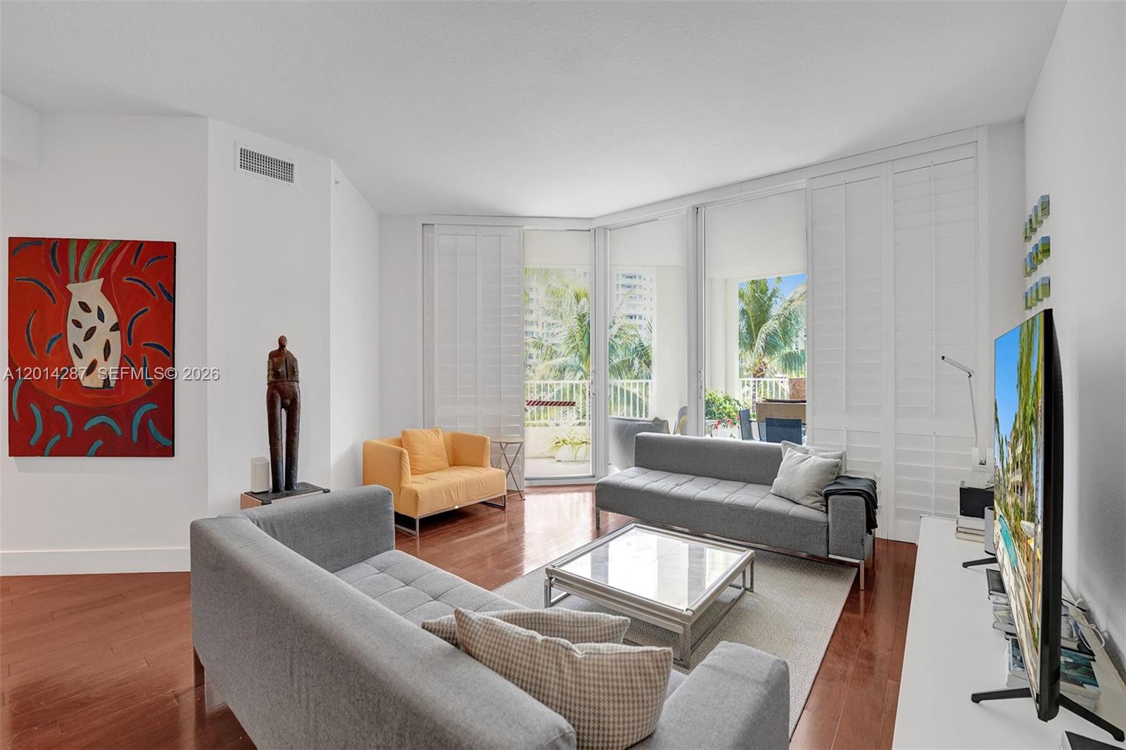A living room features two gray sofas, a yellow chair, and a glass coffee table — 715 Crandon Blvd # 406, Key Biscayne FL 33149, KEY BISCAYNE, FL