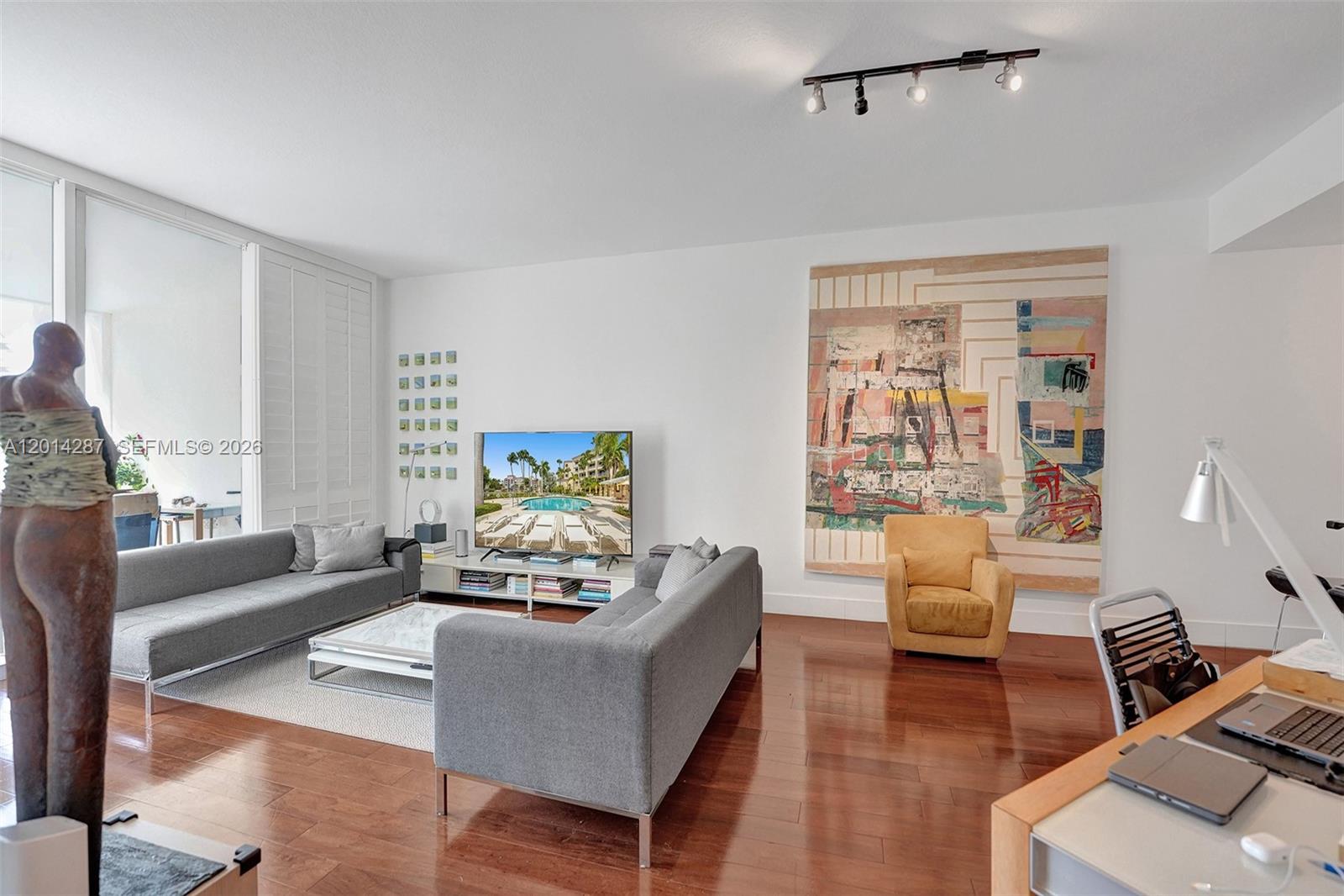 A living room features two gray sofas, a yellow armchair, and a large abstract painting — 715 Crandon Blvd # 406, Key Biscayne FL 33149, KEY BISCAYNE, FL