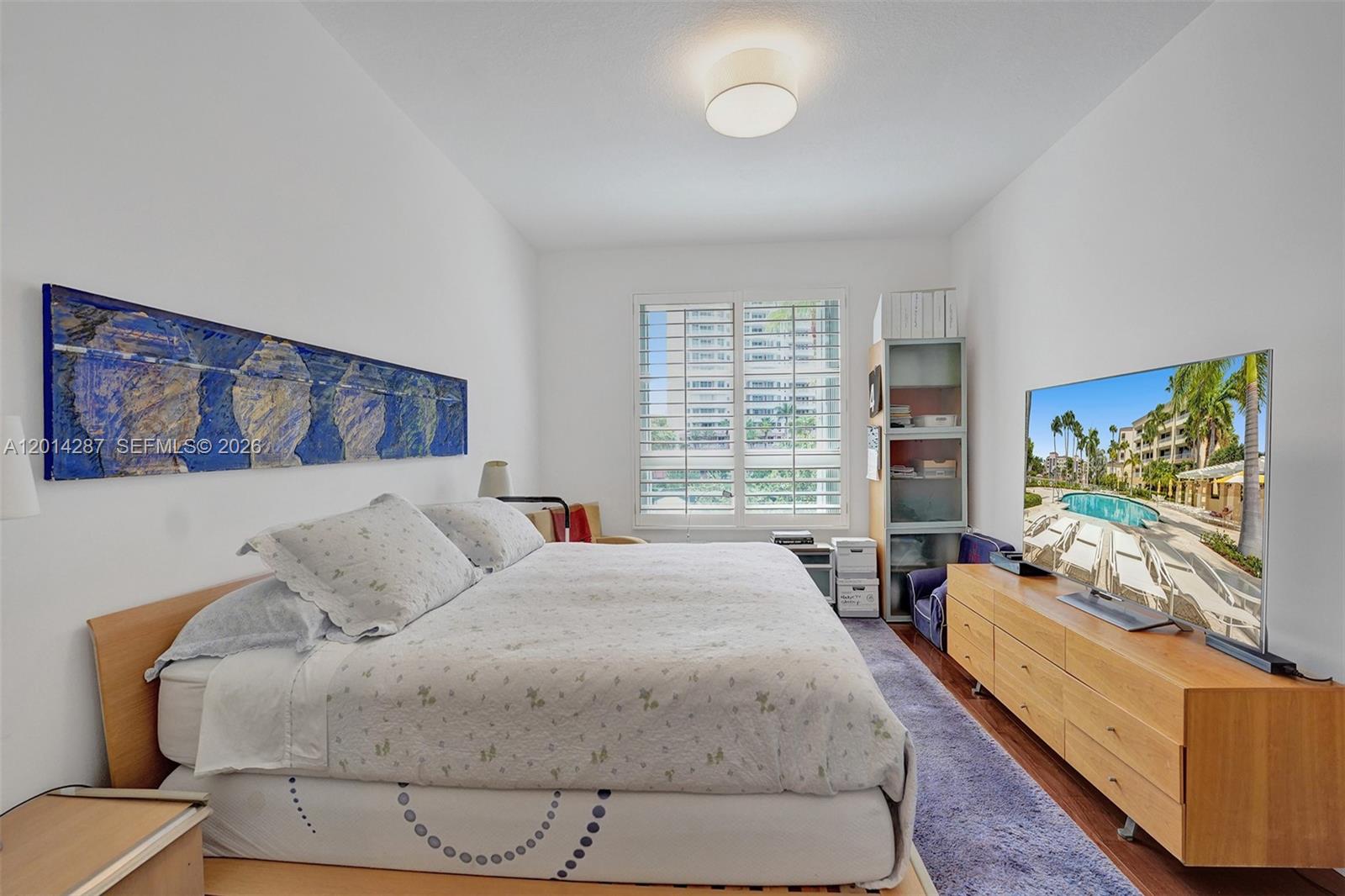 A bedroom features a platform bed, a wooden dresser with a television, and a window — 715 Crandon Blvd # 406, Key Biscayne FL 33149, KEY BISCAYNE, FL