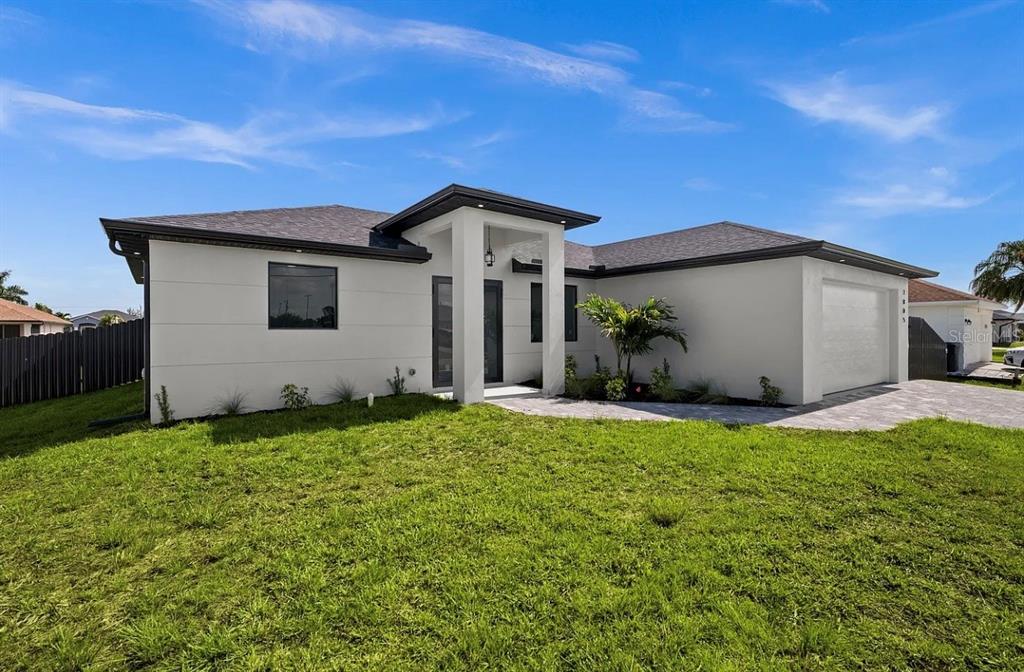 A modern, single-story white house with a dark roof and a paved driveway — 1805 NW 12TH STREET, CAPE CORAL, FL