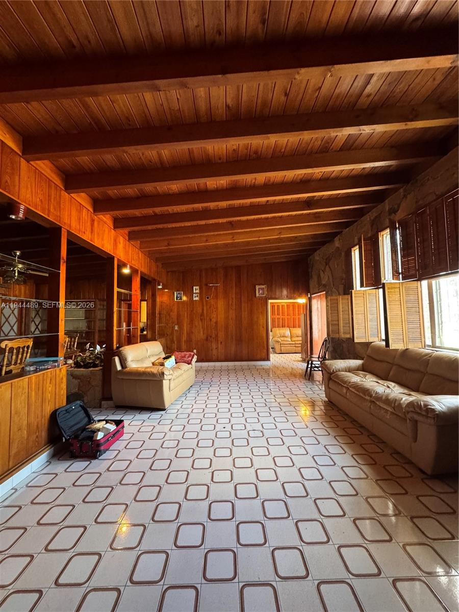 A living room features wood-paneled walls, exposed ceiling beams, and a tiled floor — 500 SW 39th Ct, Miami FL 33134, MIAMI, FL