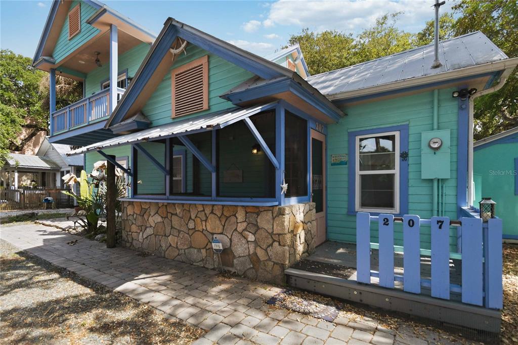 A turquoise house with a stone base, a screened porch, and a second-story balcony — 207 ESTHER STREET, NEW SMYRNA BEACH, FL