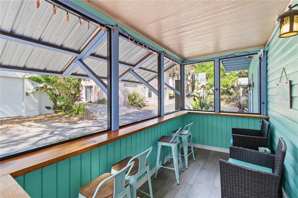 A screened-in porch features a wooden bar counter, metal stools, and teal vertical siding — 207 ESTHER STREET, NEW SMYRNA BEACH, FL