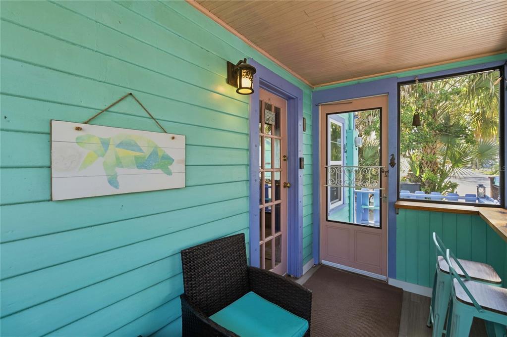A covered porch with turquoise siding, a wicker chair, and a door leading outside — 207 ESTHER STREET, NEW SMYRNA BEACH, FL