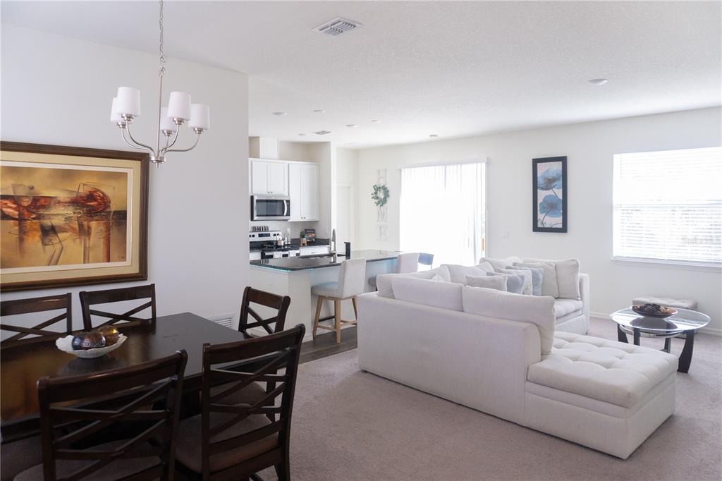 An open-concept living and dining area features a white sectional sofa and dark wood furniture — 5003 NW MANVILLE DRIVE, PORT ST LUCIE, FL
