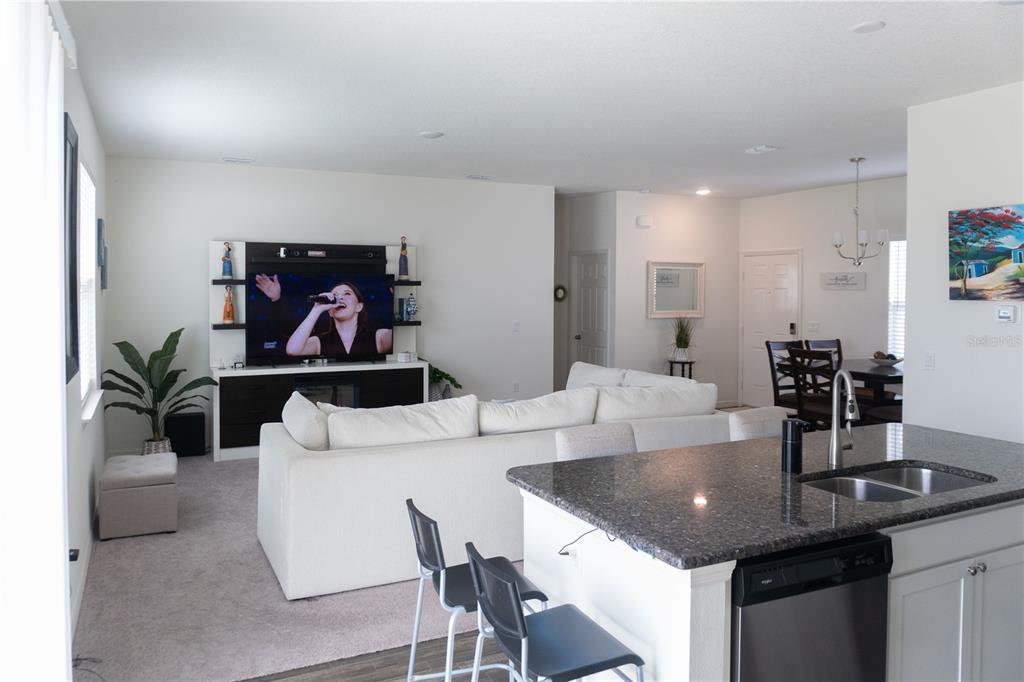 An open-concept living room and kitchen featuring a white sofa, television, and granite island — 5003 NW MANVILLE DRIVE, PORT ST LUCIE, FL