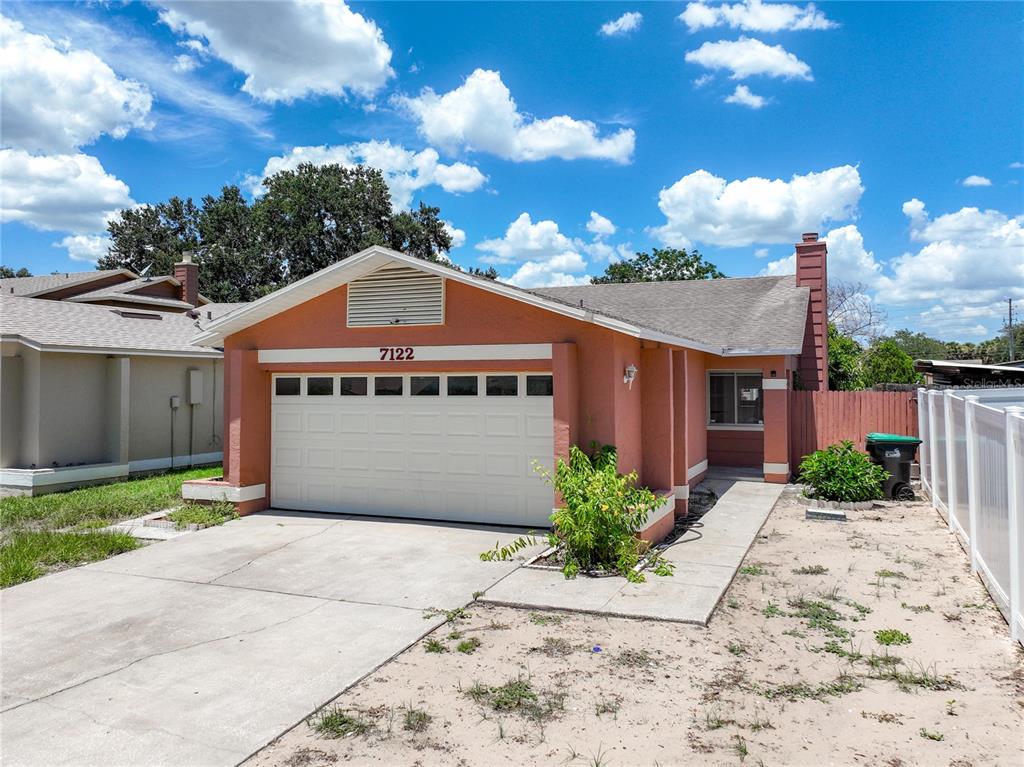 A single-story house with a peach-colored stucco exterior, a garage, and a concrete driveway — 7122 HARBOR HEIGHTS CIRCLE, ORLANDO, FL