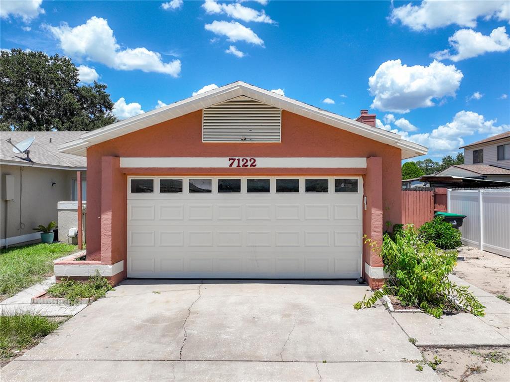 A detached garage with a white door and a terracotta-colored exterior stands under a blue sky — 7122 HARBOR HEIGHTS CIRCLE, ORLANDO, FL