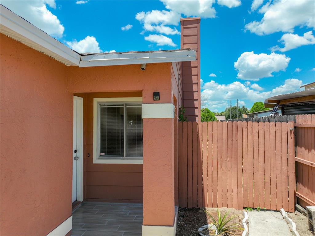 A peach-colored exterior wall features a window, a doorway, and a wooden privacy fence — 7122 HARBOR HEIGHTS CIRCLE, ORLANDO, FL