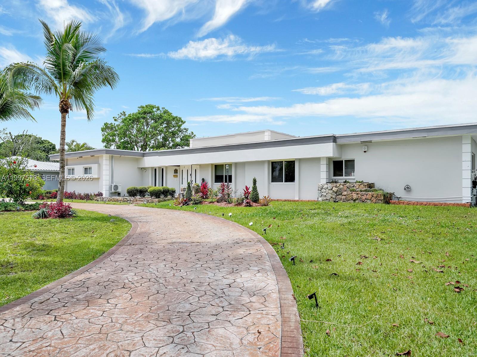 A single-story white house with a curved stone driveway and a palm tree in front — 621 E Tropical Way, Plantation FL 33317, PLANTATION, FL
