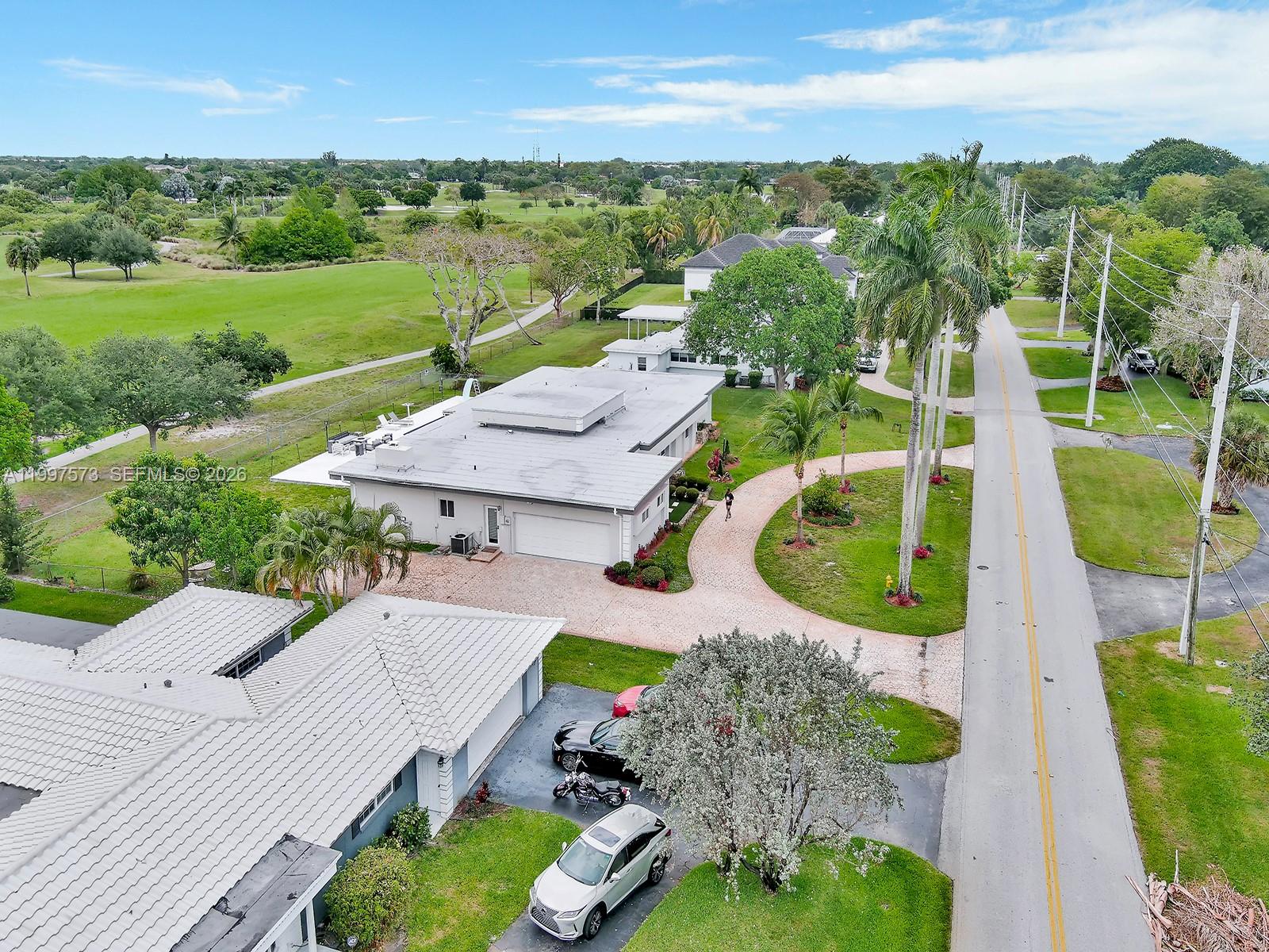 An aerial view shows a residential street with houses, a paved driveway, and a golf course — 621 E Tropical Way, Plantation FL 33317, PLANTATION, FL