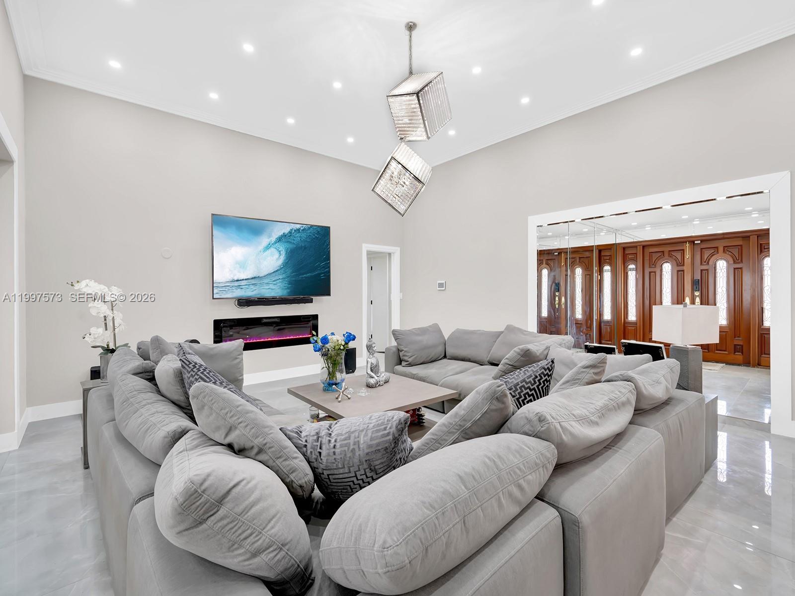 A living room features a large grey sectional sofa, a fireplace, and a television — 621 E Tropical Way, Plantation FL 33317, PLANTATION, FL