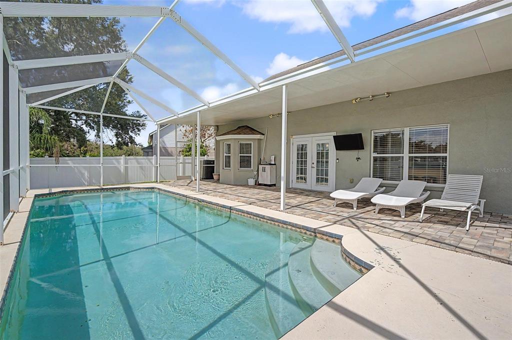 A swimming pool with steps sits on a patio enclosed by a screened-in lanai — 24520 SUMMER WIND COURT, LUTZ, FL