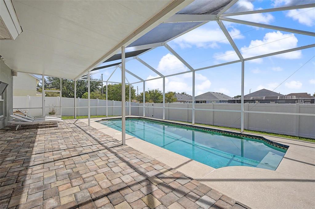 A rectangular swimming pool sits on a paved patio inside a screened-in enclosure — 24520 SUMMER WIND COURT, LUTZ, FL