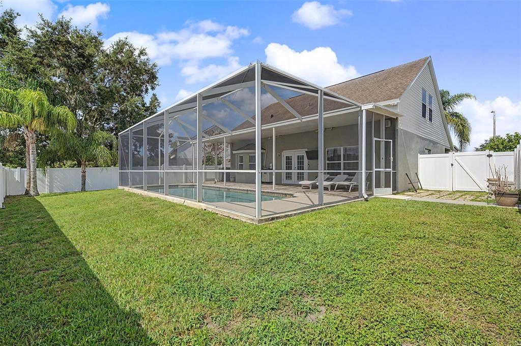 A backyard features a swimming pool enclosed by a screened lanai attached to a house — 24520 SUMMER WIND COURT, LUTZ, FL