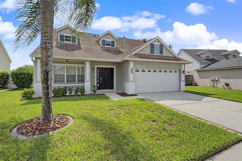 A two-story suburban house with a white garage, a front door, and a palm tree — 24520 SUMMER WIND COURT, LUTZ, FL