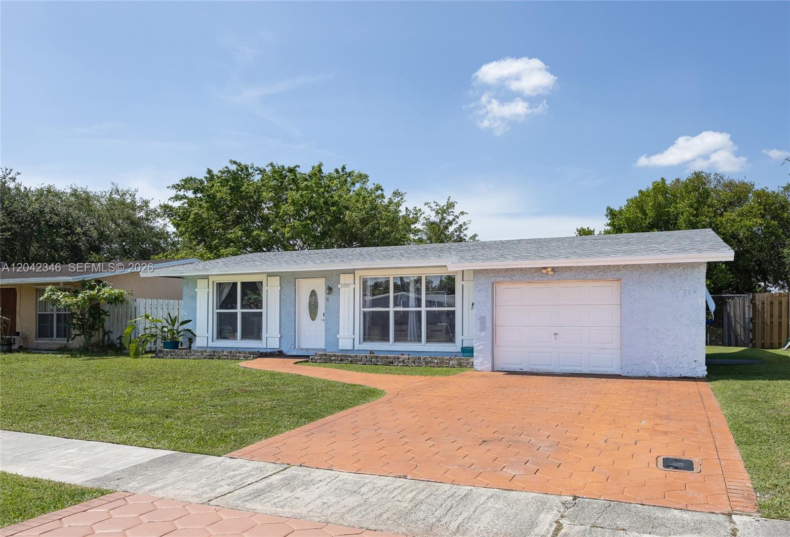 A single-story house with a light blue exterior, a white garage door, and a paved driveway — 8350 NW 27th Pl, Sunrise FL 33322, SUNRISE, FL