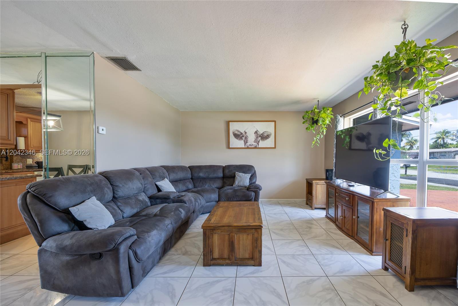 A living room features a large gray sectional sofa, a wooden coffee table, and tile flooring — 8350 NW 27th Pl, Sunrise FL 33322, SUNRISE, FL