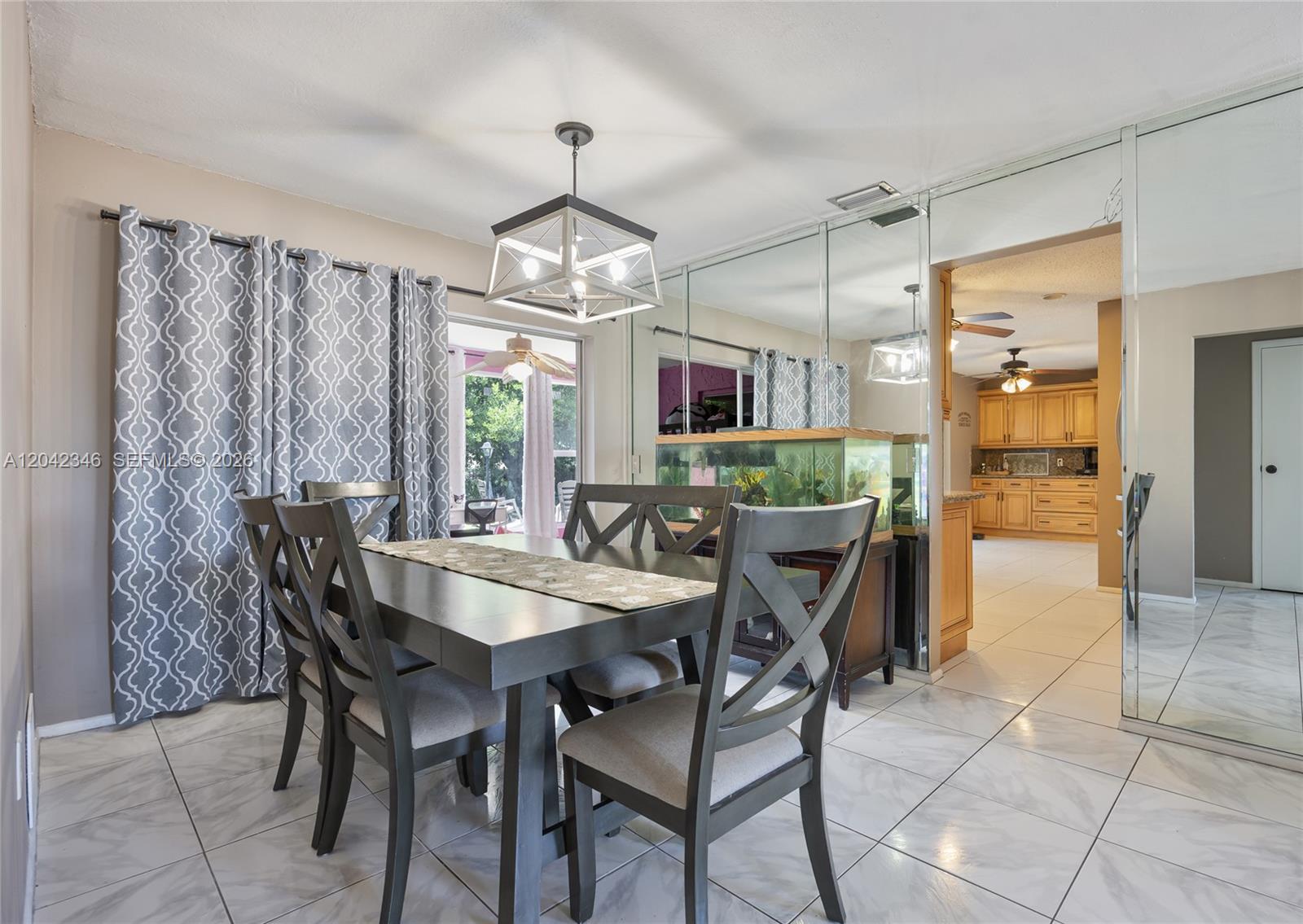 A dining room features a dark wood table, gray chairs, a chandelier, and mirrored walls — 8350 NW 27th Pl, Sunrise FL 33322, SUNRISE, FL