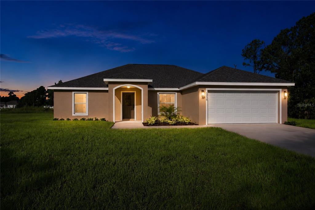 A single-story house with a tan stucco exterior, a two-car garage, and a front entrance — 6898 DICKINSON DRIVE, SEBRING, FL