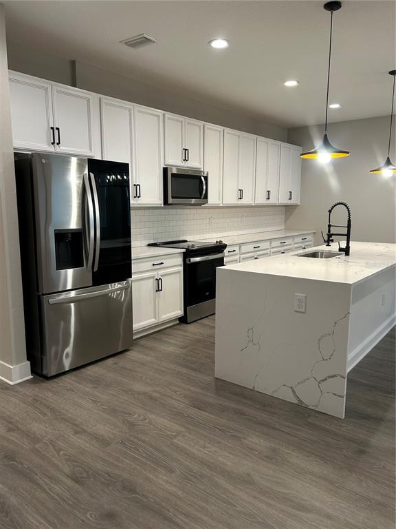 A modern kitchen features white cabinets, stainless steel appliances, and a marble-topped island — 2556 13TH AVENUE N, ST PETERSBURG, FL