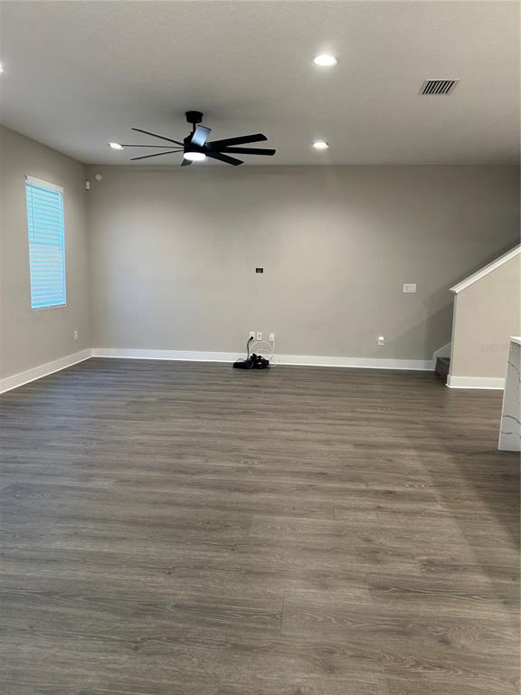 An empty living room features gray walls, wood-look flooring, a ceiling fan, and recessed lighting — 2556 13TH AVENUE N, ST PETERSBURG, FL
