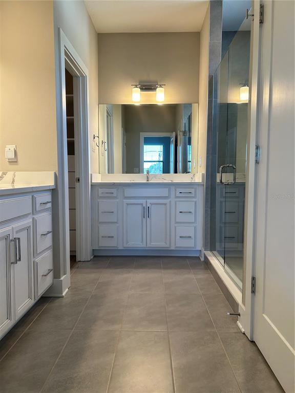 A bathroom features a white vanity with a marble countertop, a mirror, and a glass shower — 2556 13TH AVENUE N, ST PETERSBURG, FL