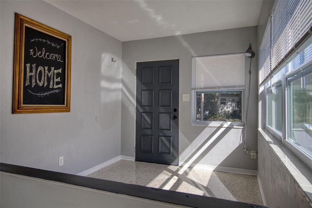 An entryway features a gray door, light gray walls, a chalkboard sign, and terrazzo flooring — 634 15 AVENUE S, ST PETERSBURG, FL