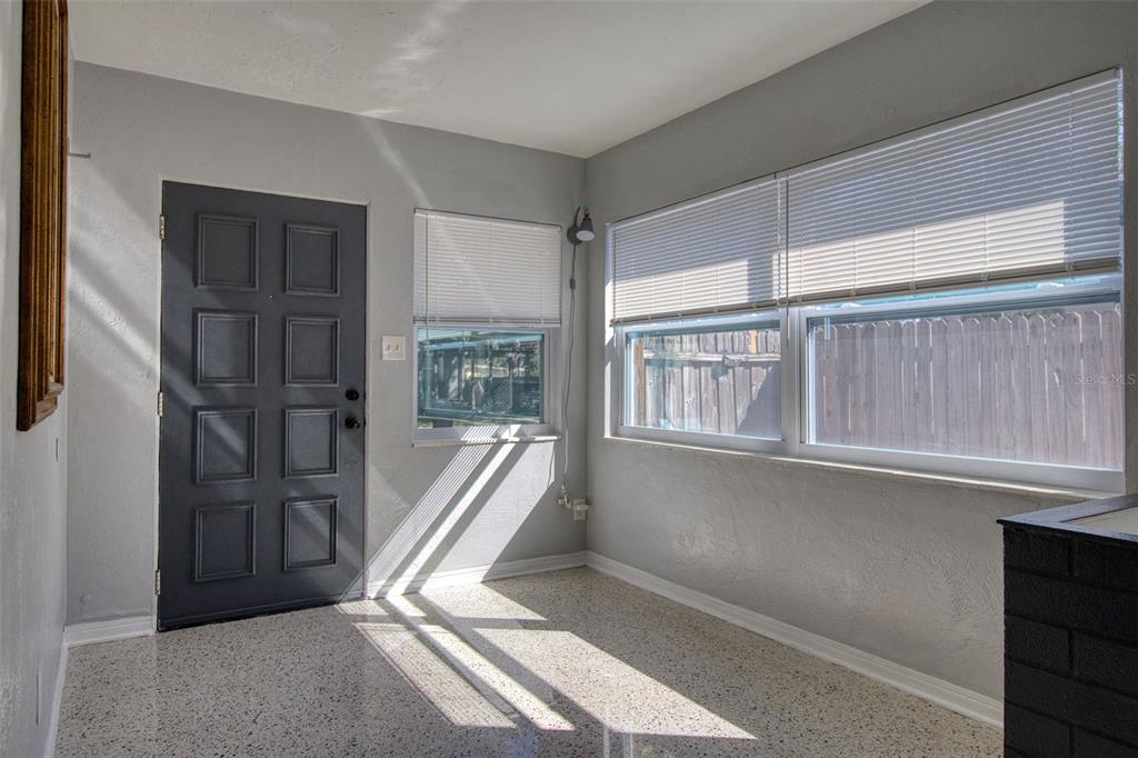 A sunroom with gray walls, a dark gray door, and speckled terrazzo flooring — 634 15 AVENUE S, ST PETERSBURG, FL