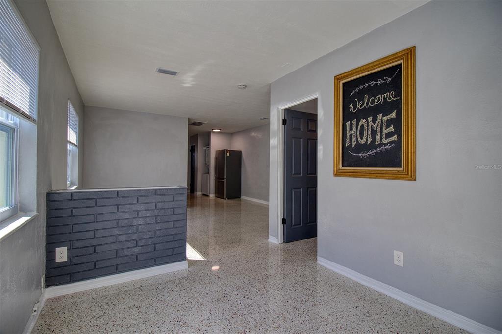 An interior view shows a room with gray walls, a brick half-wall, and terrazzo flooring — 634 15 AVENUE S, ST PETERSBURG, FL
