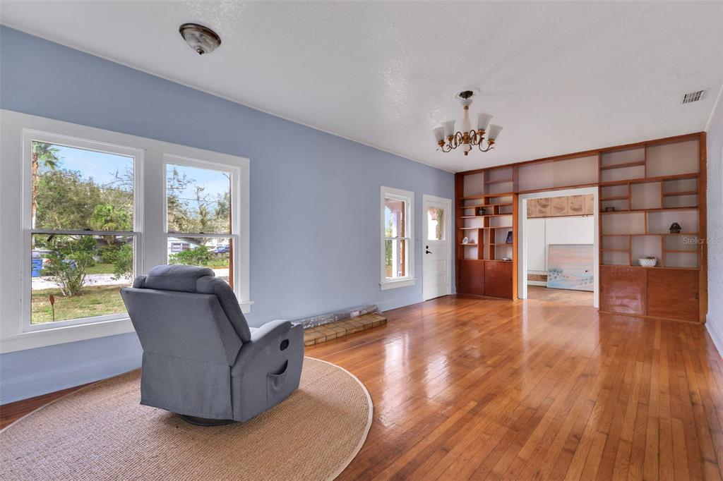 A living room with hardwood floors, a gray recliner, and built-in wooden shelving units — 742 HIBISCUS AVENUE, LAKE WALES, FL