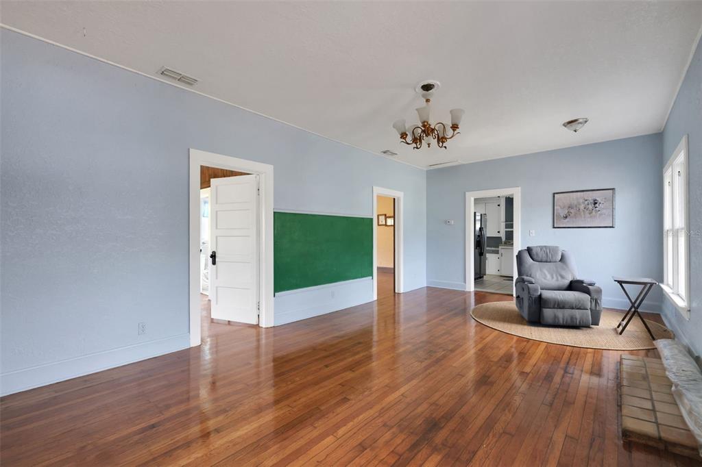 A living room with light blue walls, hardwood floors, a chalkboard, and a gray recliner — 742 HIBISCUS AVENUE, LAKE WALES, FL
