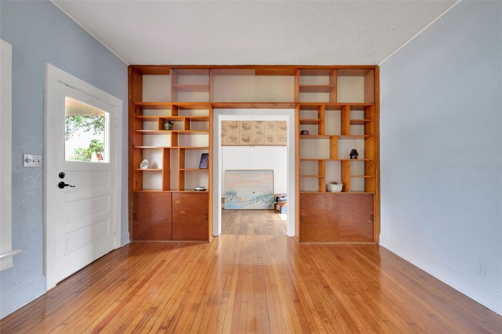 A room with hardwood floors features a large built-in wooden bookshelf surrounding a central doorway — 742 HIBISCUS AVENUE, LAKE WALES, FL