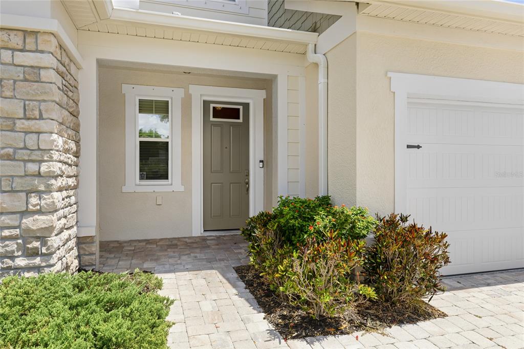 The exterior of a home features a stone-accented wall, a covered entryway, and a garage — 3644 TIN CUP BOULEVARD, SARASOTA, FL
