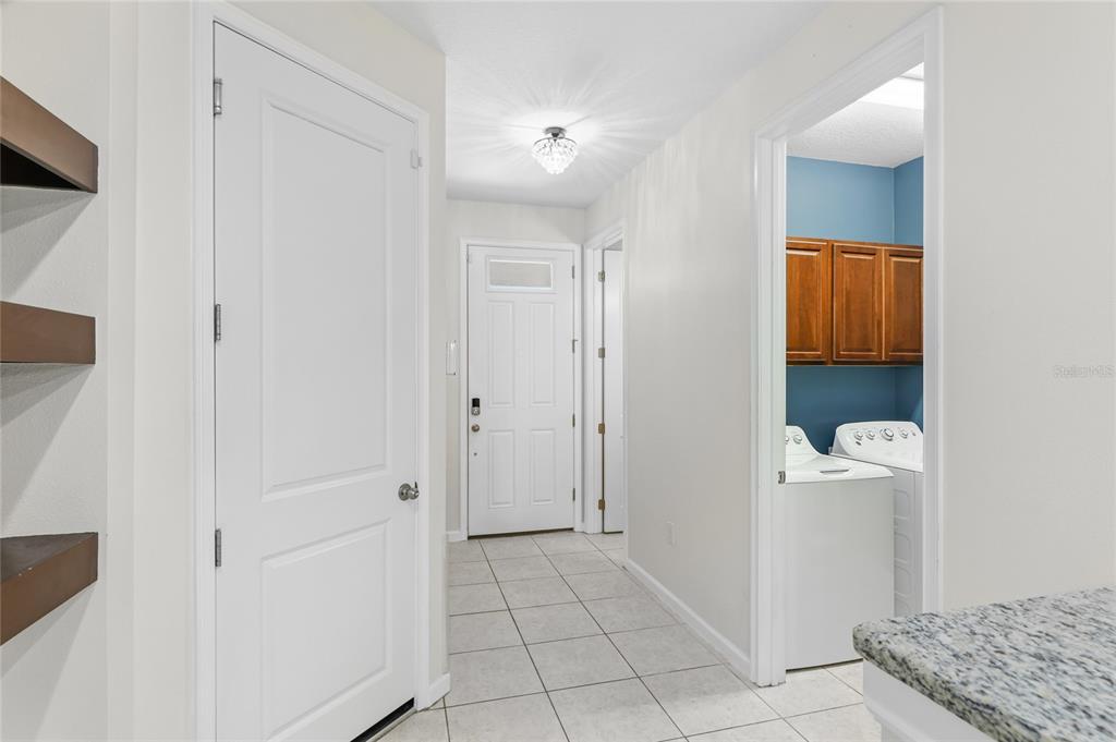 A hallway with tiled floors leads to a front door, a laundry room, and doors — 3644 TIN CUP BOULEVARD, SARASOTA, FL
