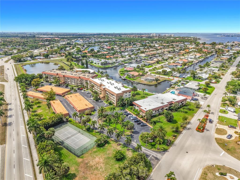 An aerial view shows a multi-building residential complex with a tennis court and canal access — 4277 MARINER WAY UNIT 218, FORT MYERS, FL