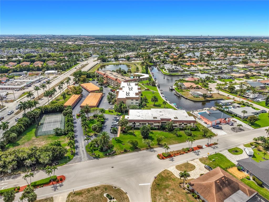 An aerial view shows a multi-building apartment complex with a tennis court and canal — 4277 MARINER WAY UNIT 218, FORT MYERS, FL