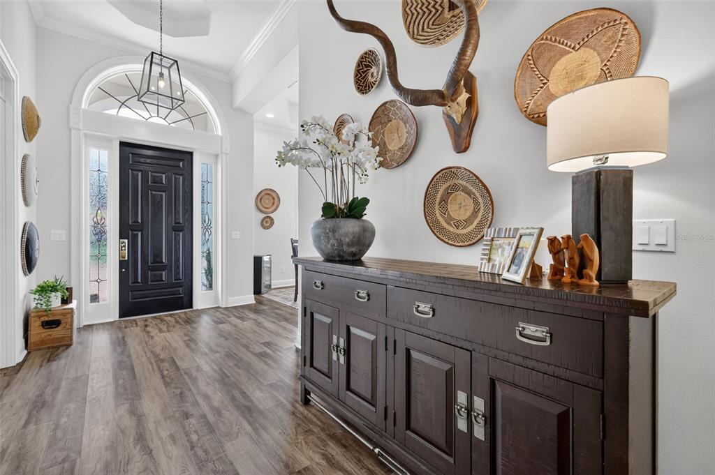 An entryway features a dark wood console table, wall-mounted woven baskets, and a black front door — 9616 SAN FERNANDO COURT, HOWEY IN THE HILLS, FL