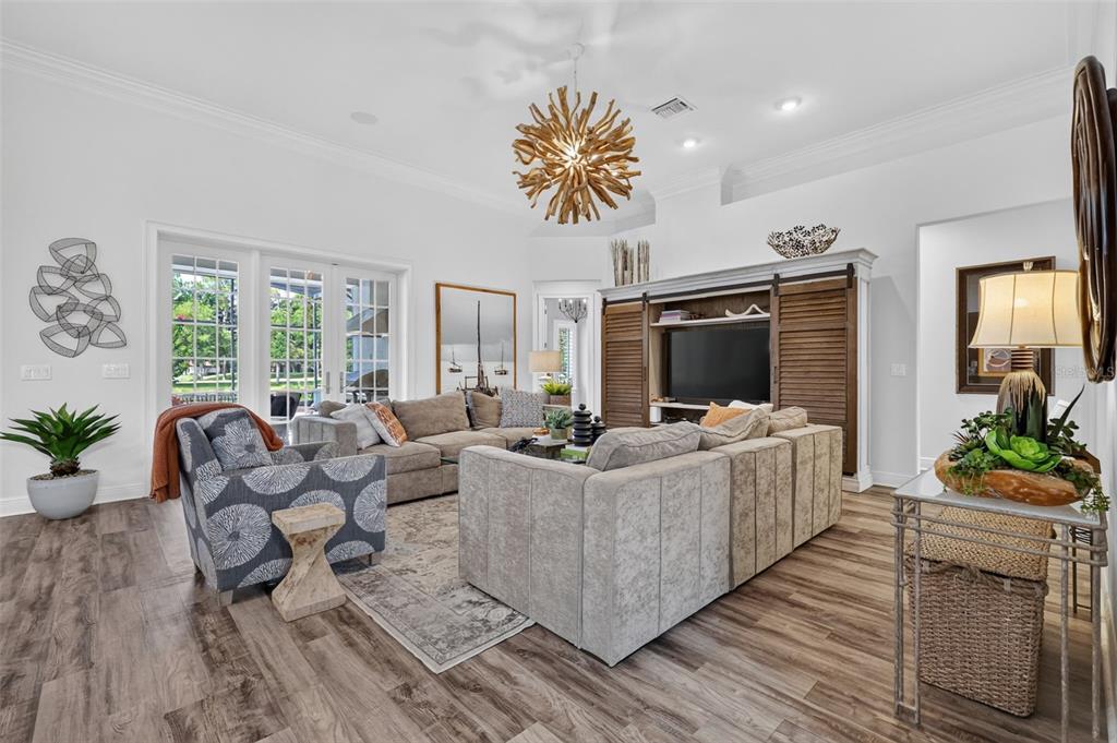 A living room features a large sectional sofa, a wooden entertainment center, and a chandelier — 9616 SAN FERNANDO COURT, HOWEY IN THE HILLS, FL