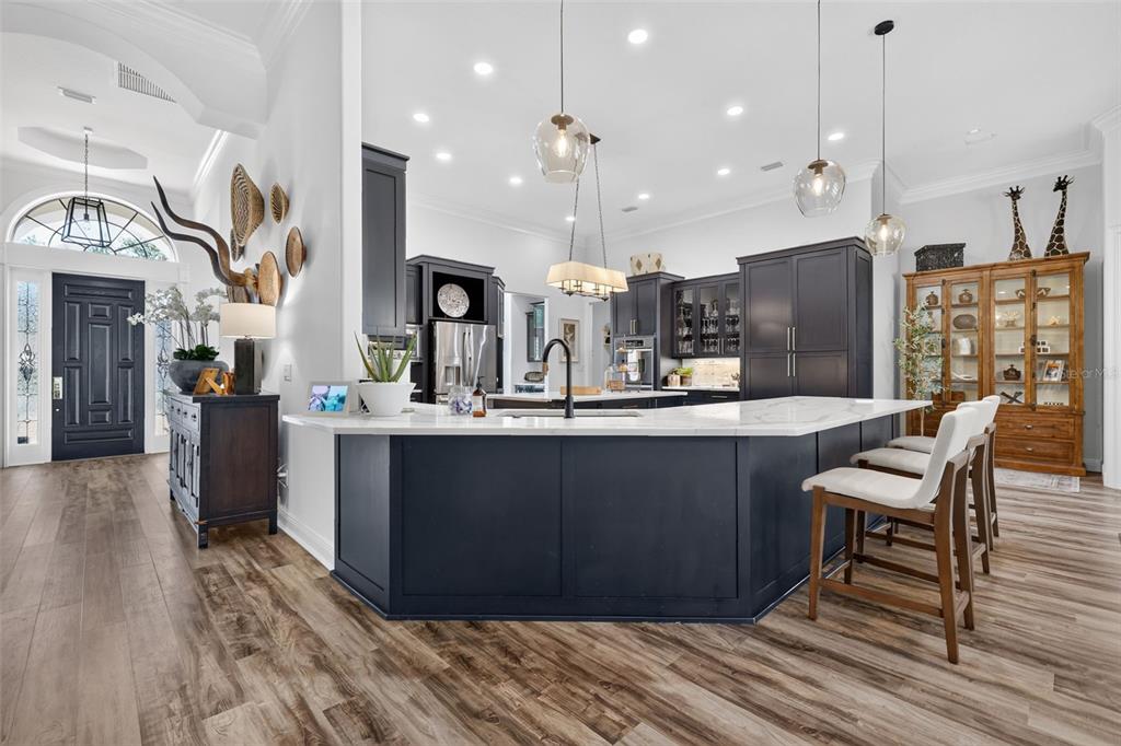 A kitchen features dark blue cabinetry, a white marble island, and light wood flooring — 9616 SAN FERNANDO COURT, HOWEY IN THE HILLS, FL