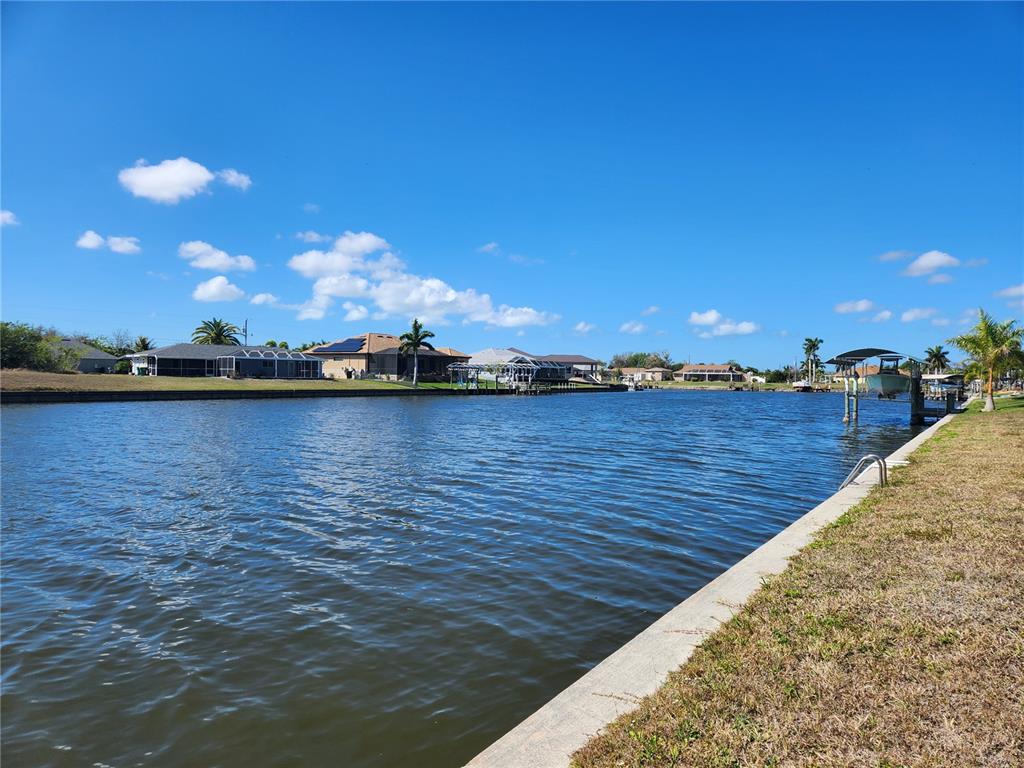 A view of a canal lined with residential houses and private boat docks under blue skies — 15332 ALSASK CIRCLE, PORT CHARLOTTE, FL