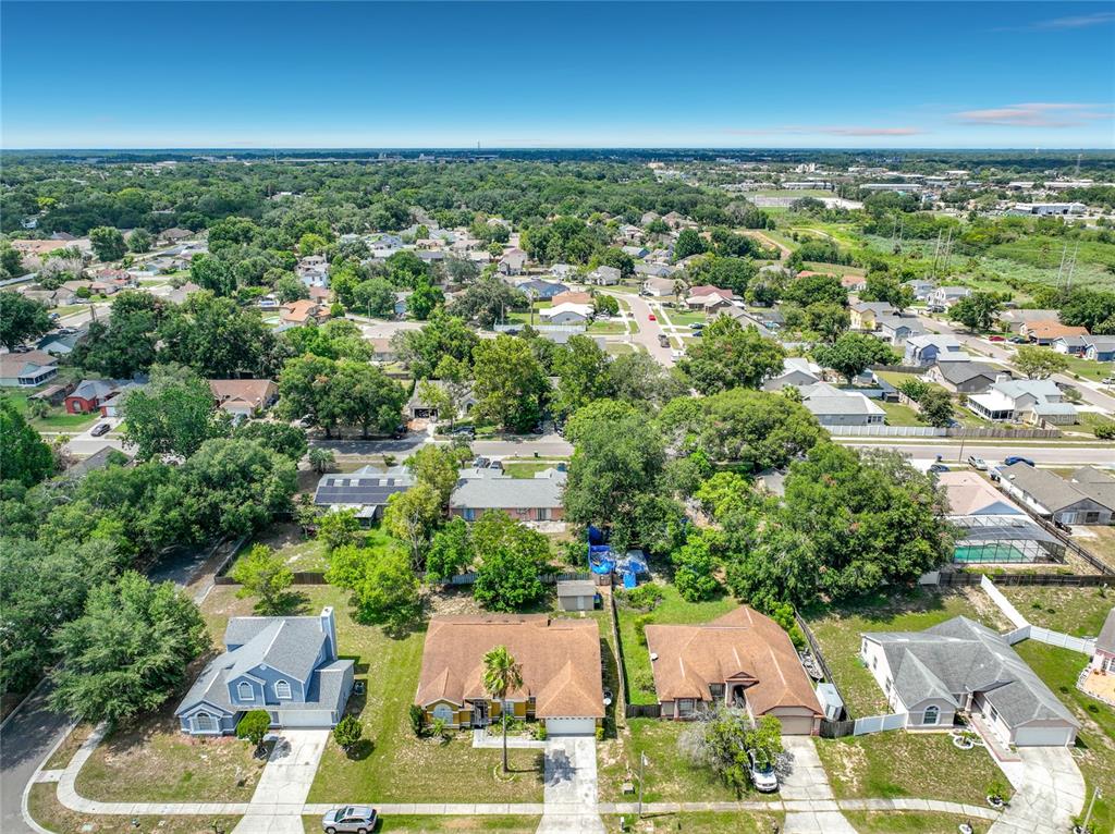 An aerial view shows a suburban neighborhood with single-family homes, mature trees, and paved streets — 5579 RED BONE LANE, ORLANDO, FL