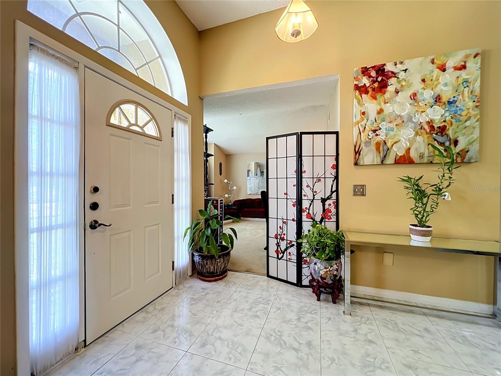 A tiled entryway features a white front door, a folding screen, and a console table — 5579 RED BONE LANE, ORLANDO, FL