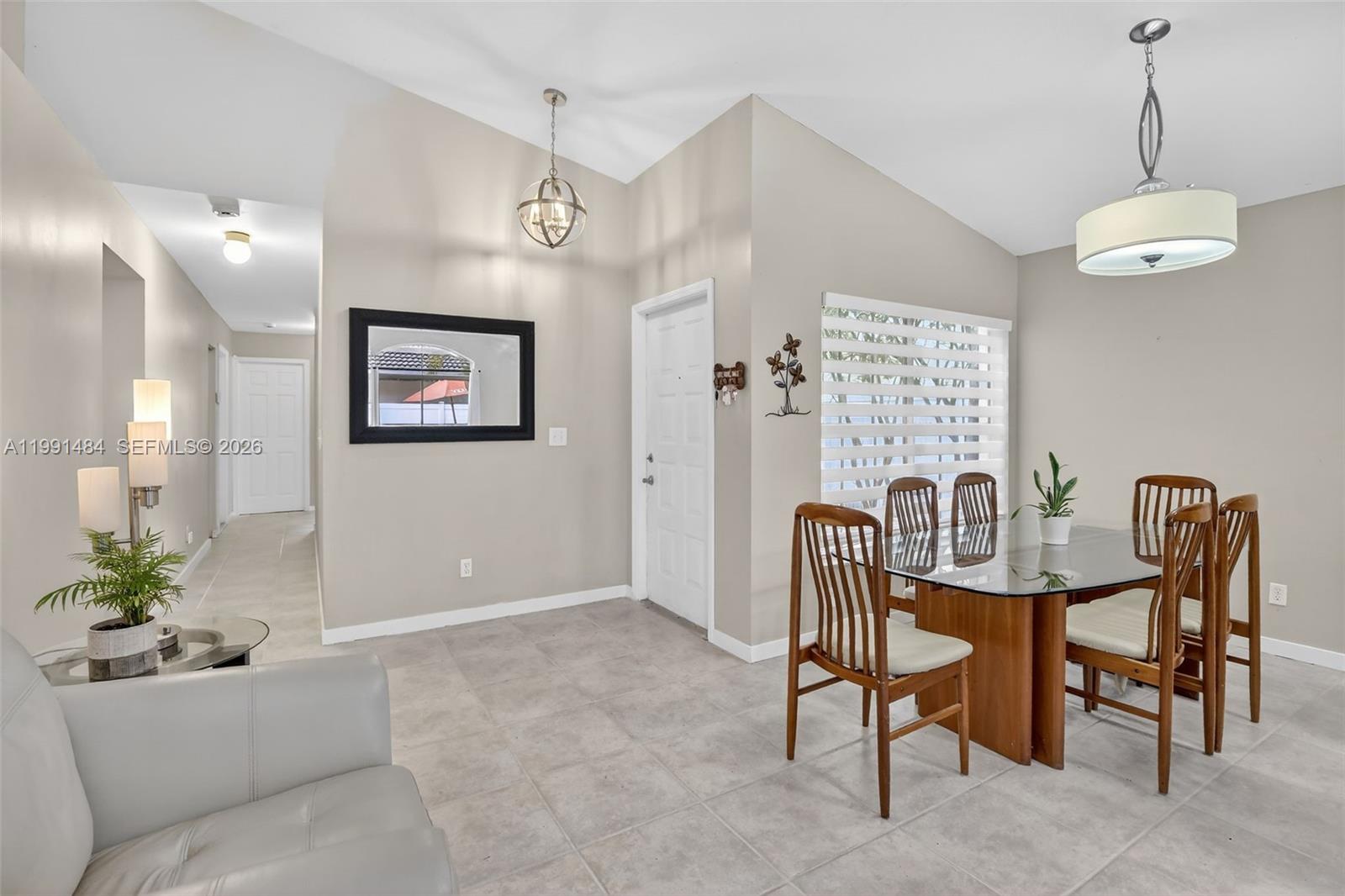An open-concept living and dining area features tile flooring, a kitchen island, and sliding doors — 922 Opal Ter, Weston FL 33326, WESTON, FL