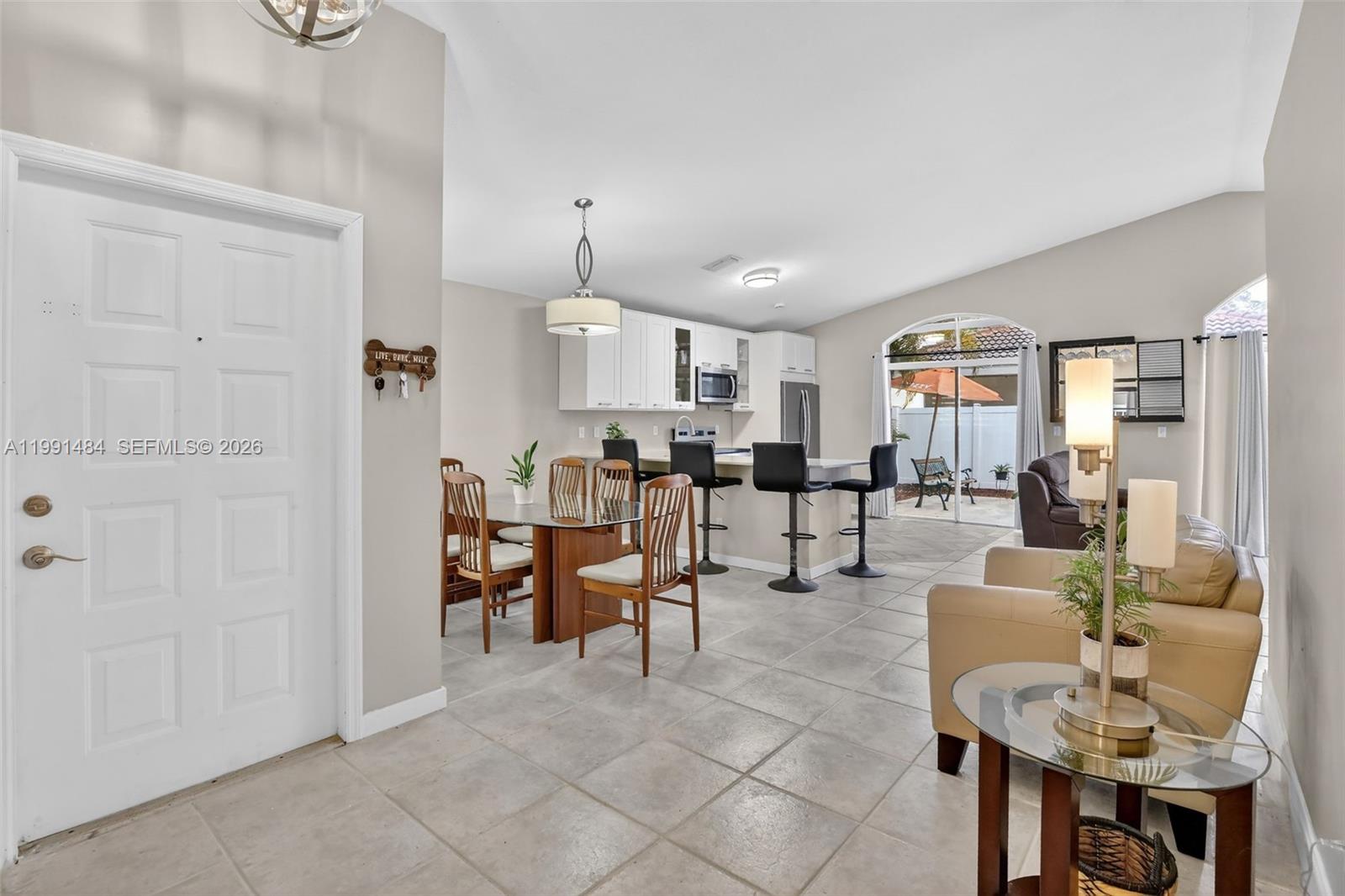 A dining area with a glass table, wooden chairs, tile flooring, and a vaulted ceiling — 922 Opal Ter, Weston FL 33326, WESTON, FL