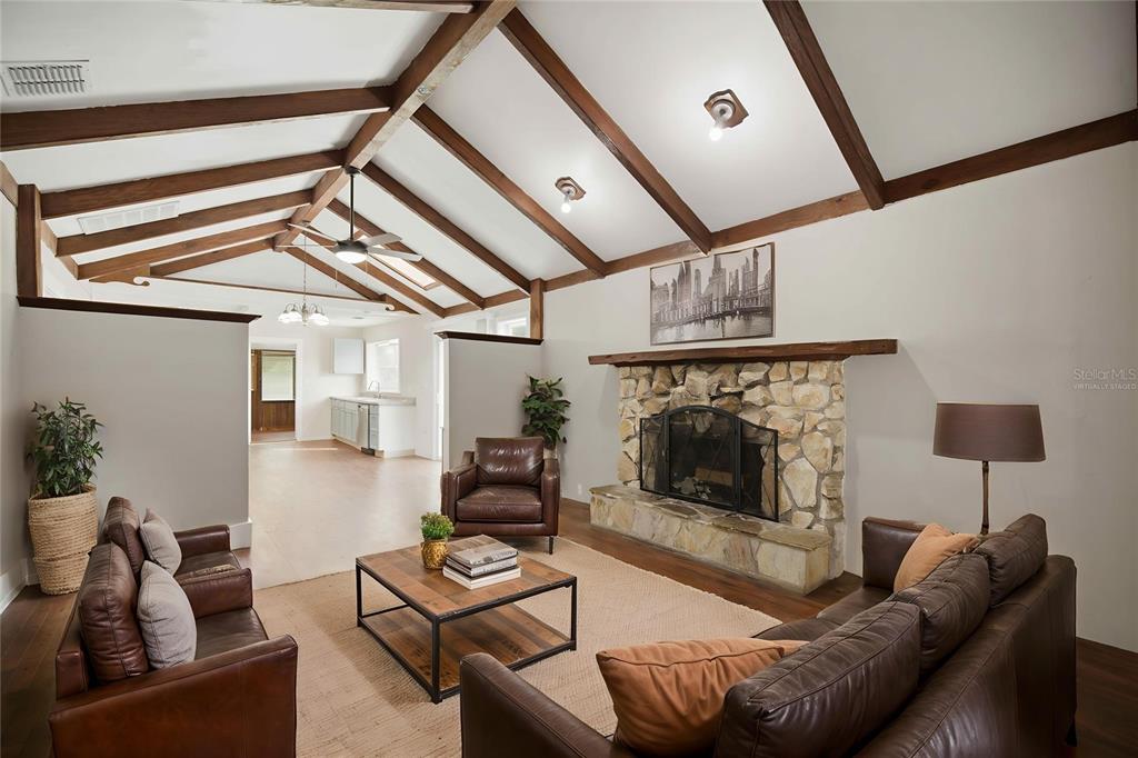 A living room features a vaulted ceiling with exposed beams, a stone fireplace, and leather furniture — 2107 NE 8TH ROAD, OCALA, FL