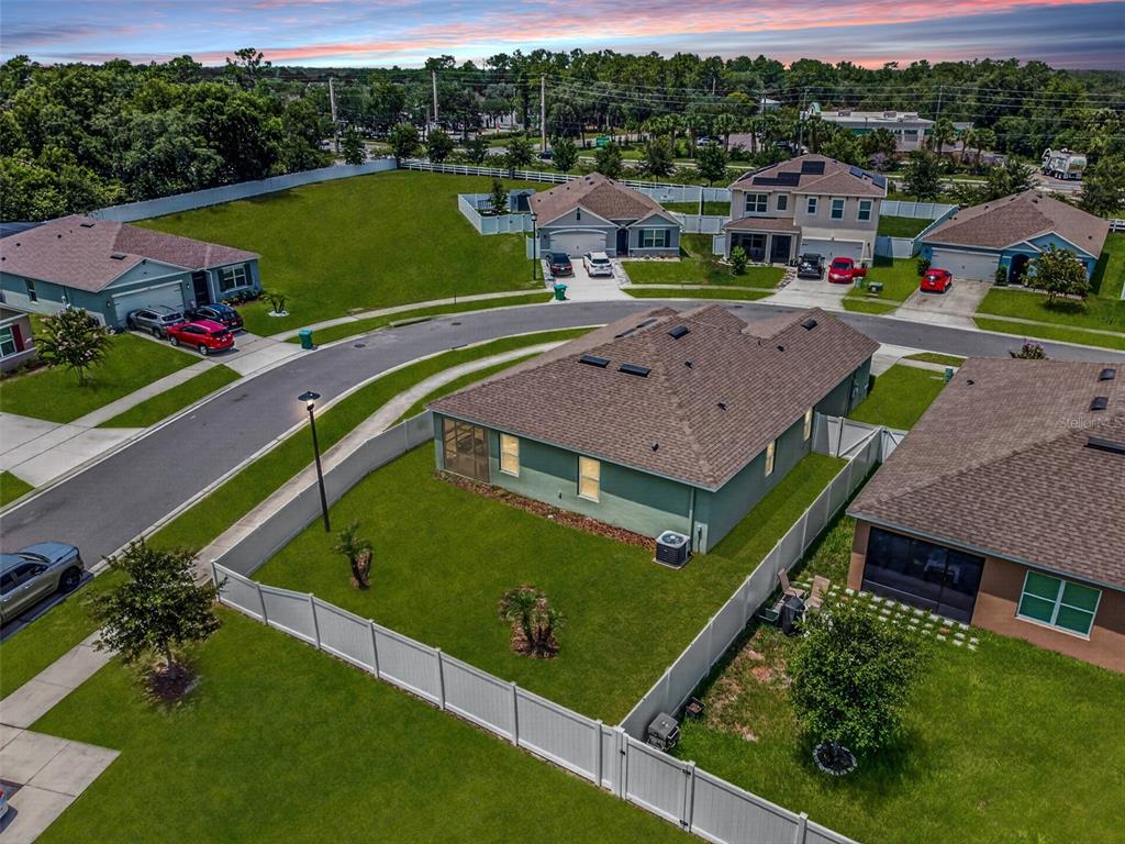 An aerial view shows a suburban neighborhood with single-family homes, fenced yards, and paved streets — 1097 AUGUST SKY DRIVE, DELTONA, FL